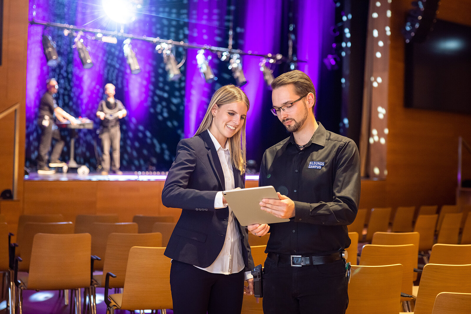 Foto zeigt eine Frau und einen Mann mit einem Ipad im AULA Saal